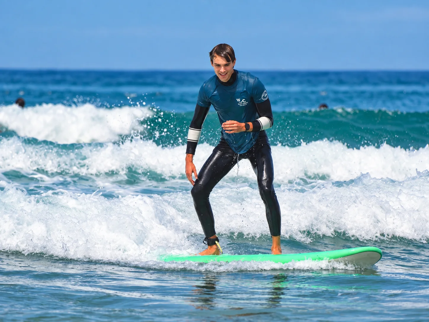 Student practicing their stance on a green surfboard.